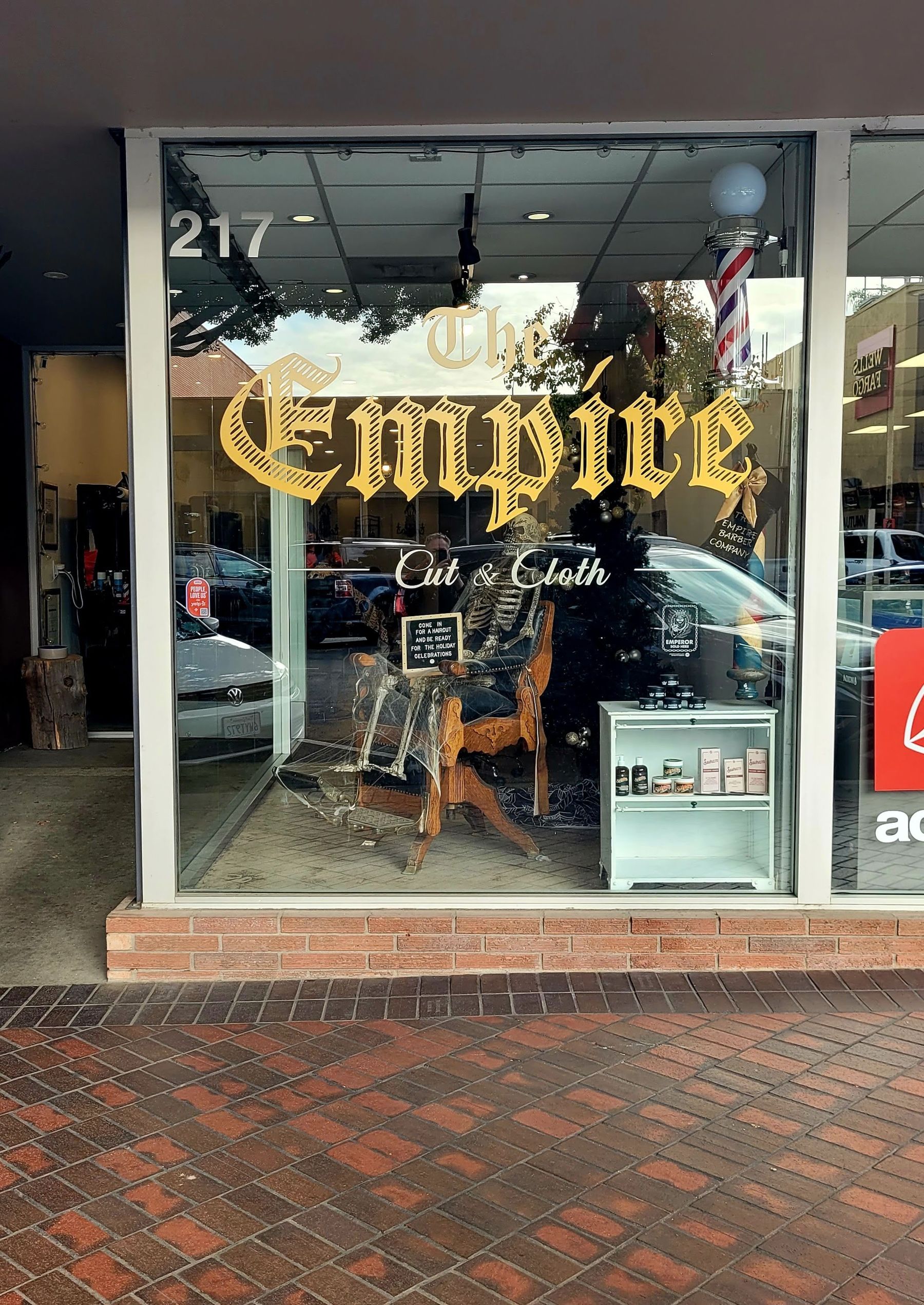 The Empire Barber Company's front window at 217 E State St: gold THE EMPIRE lettering, a barber pole, and a skeleton in a wooden barber chair